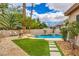 This backyard features a refreshing pool, green grass, pavers, and comfortable seating for outdoor relaxation at 7730 Brambly Creek Ct, Las Vegas, NV 89129