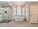 Luxurious bathroom features a soaking tub with modern chandelier and glass shower at 7730 Brambly Creek Ct, Las Vegas, NV 89129