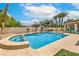 Backyard view of a sparkling pool and spa, complemented by palm trees and outdoor seating under a clear, blue sky at 7730 Brambly Creek Ct, Las Vegas, NV 89129