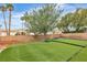 Lush backyard with artificial grass, mature trees, and private putting green for outdoor enjoyment at 7929 Ben Hogan Dr, Las Vegas, NV 89149