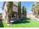 A well manicured backyard featuring artificial turf, lush trees and a covered patio at 852 Colina Alta Pl, Las Vegas, NV 89138