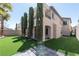 An open backyard with lush artifical grass, tall slender trees, and a covered patio at 852 Colina Alta Pl, Las Vegas, NV 89138