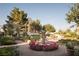 Beautiful backyard featuring a large fountain surrounded by roses, lush landscaping, and mature trees at 8620 W La Madre Way, Las Vegas, NV 89149