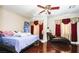 Cozy bedroom featuring a comfortable bed with a blue comforter, a ceiling fan, and hardwood floors at 9856 Chief Sky St, Las Vegas, NV 89178