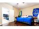 Bedroom featuring a full sized bed, hardwood floors, and an adjoining living room with television at 9856 Chief Sky St, Las Vegas, NV 89178