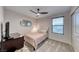 Bright bedroom boasts neutral tones, plush carpet, ceiling fan, and a window with bright sunlight at 10025 San Floriano St, Las Vegas, NV 89178