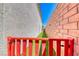 The side yard features a well maintained and luscious artificial lawn, enclosed by a red gate and brick wall at 10025 San Floriano St, Las Vegas, NV 89178