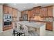 Beautiful kitchen island with a light countertop, wooden cabinetry, and three patterned bar stools at 1005 Old Creek Way, North Las Vegas, NV 89084