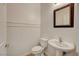 Half bathroom with wainscoting, pedestal sink, decorative mirror, and neutral color palette at 1055 Fish Pond Ave, Henderson, NV 89014