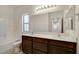 Bathroom featuring dual sinks, sleek countertops, a large mirror, and a combination bathtub shower at 1055 Fish Pond Ave, Henderson, NV 89014