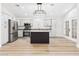 A modern kitchen features stainless steel appliances, white cabinetry, and a dark island with granite countertops at 1305 Pagentry Dr, North Las Vegas, NV 89031