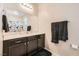 Well-lit bathroom featuring dark cabinetry, white countertops, and a large mirror showcasing a shower with patterned curtain at 1641 Blue Cliffs Ave, Henderson, NV 89014