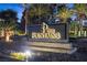 Illuminated 'The Fountains' community sign with lush landscaping and palm trees at dusk at 2268 Buckingham Ct, Henderson, NV 89074