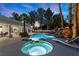 Twilight view of a backyard with pool, spa, rock waterfall, lounge chairs, and palm trees at 2268 Buckingham Ct, Henderson, NV 89074