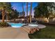 Backyard oasis with a sparkling pool, spa, rock features, palm trees, and lush landscaping at 2268 Buckingham Ct, Henderson, NV 89074