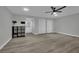 Spacious, grey-toned living room with a ceiling fan and gray wood-look floors, leading to a white front door at 2635 Heritage Ct, Las Vegas, NV 89121