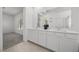 Bright bathroom featuring dual sinks, white cabinets, large mirror, and view into the bedroom from the bathroom at 3706 Etendre Ct, Las Vegas, NV 89121