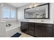 Bathroom featuring a soaking tub, dual sinks, dark wood cabinetry and a large mirror at 3854 Stadium Ave, Las Vegas, NV 89120