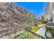 The backyard has grass between the paver stones, a rock wall and built in landscaping at 414 Tranquil Peak Ct, Henderson, NV 89012