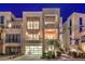 Night shot of a modern home displaying multiple balconies, a glass garage door, and professional landscaping at 414 Tranquil Peak Ct, Henderson, NV 89012