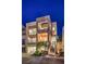 Dusk image of a modern home with a glass garage door, multiple balconies, and landscaped yard with lighting at 414 Tranquil Peak Ct, Henderson, NV 89012