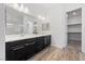 Elegant bathroom with dual sinks, black vanity, large mirror, and wood-look floors at 485 Pebble Run Ave, Henderson, NV 89011