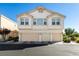 Inviting townhouse featuring a three-car garage and cream-colored facade under a clear blue sky at 6549 Clara Bow Ave # 103, Las Vegas, NV 89122