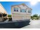 Inviting townhouse featuring a three-car garage and cream-colored facade under a clear blue sky at 6549 Clara Bow Ave # 103, Las Vegas, NV 89122
