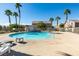 Community pool with tall palm trees and lounge chairs, set against a backdrop of residential houses at 6549 Clara Bow Ave # 103, Las Vegas, NV 89122