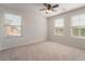 Bedroom featuring neutral carpet, ceiling fan, and three windows providing natural light at 7083 Seat Wall Rd, Las Vegas, NV 89148