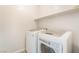 Bright laundry room featuring a front-load washer and dryer and storage shelf at 7083 Seat Wall Rd, Las Vegas, NV 89148