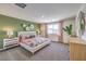 Bright bedroom featuring stylish decor, a queen-sized bed with patterned bedding, and large windows with pink curtains at 790 Calm Crystal Ct # Lot 140, North Las Vegas, NV 89081
