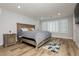 Relaxing bedroom featuring hardwood floors, a plush bed, and sun-filled windows with modern shutters at 8095 Carpenter Creek Ave, Las Vegas, NV 89113