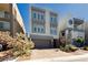 Modern three-story home boasting a gray exterior, brick driveway, and manicured landscaping at 8095 Carpenter Creek Ave, Las Vegas, NV 89113