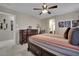Brightly lit bedroom features a ceiling fan, a large bed with matching dressers, and decorative wall art at 9046 Barium Rock Ave, Las Vegas, NV 89143