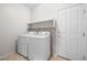 Functional laundry room with white appliances, shelving, and a door to the exterior at 9282 W Viking Rd, Las Vegas, NV 89147