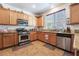Well-maintained kitchen with stainless steel appliances, wooden cabinets, and a view of the dining area at 9513 Perennial View Ave, Las Vegas, NV 89148
