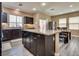 Spacious kitchen featuring an island with granite countertops, dark wood cabinets, and stainless steel appliances at 10519 Mann St, Las Vegas, NV 89141