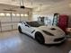 Clean, spacious garage with a white Corvette, storage cabinets, and epoxy flooring at 10832 Heritage Hills Dr, Las Vegas, NV 89134