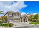 Two-story home with a combination of gray stucco and stone accents, three-car garage, and manicured lawn at 2959 Azure Bay St, Las Vegas, NV 89117