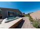 Backyard features a hot tub, patio, lush landscaping, and partial view of the home's exterior at 32 Via Del Fiume, Henderson, NV 89011