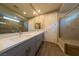 Bathroom with double vanity, quartz countertop, tile flooring, large mirror, and large glass enclosed shower with tile surround at 32 Via Del Fiume, Henderson, NV 89011