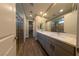 Bathroom with double vanity, quartz countertop, tile flooring, large mirror, and glass enclosed shower with a built in bench at 32 Via Del Fiume, Henderson, NV 89011