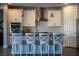 Kitchen featuring an island with seating, white cabinets, stainless steel appliances, and modern pendant lighting at 32 Via Del Fiume, Henderson, NV 89011