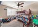 Cozy bedroom featuring a ceiling fan, a large window, and a wooden bunk bed with colorful bedding and a fun design at 5804 Apple Valley Ln, Las Vegas, NV 89108