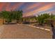 Charming single-story home with gravel landscaping, wood fence, and a beautiful desert sunset at 5822 E Carey Ave, Las Vegas, NV 89156