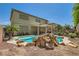 Serene backyard featuring a custom pool with rock accents, a covered patio, and mature landscaping for privacy at 6329 Orange Hue St, North Las Vegas, NV 89031