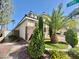 Well-manicured front yard with lush green grass, brick walkway, palm trees and flowering bushes at 640 House Blend Ln, Henderson, NV 89052