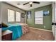 Bedroom featuring a ceiling fan, natural light, neutral carpet and olive accent wall at 680 Moonlight Stroll St, Henderson, NV 89002