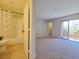 Bright main bedroom with a balcony, neutral colors, and attached bathroom featuring a shower and bathtub at 6853 Tamarus St # 202, Las Vegas, NV 89119